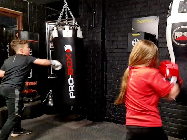 Children training on heavy punching bags with boxing gloves at Boxing Fitness MK