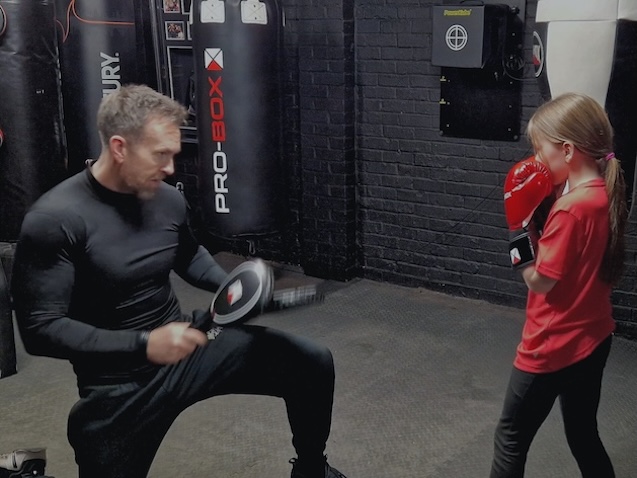 Boxing coach conducting pad work training with junior boxer at Boxing Fitness MK gym