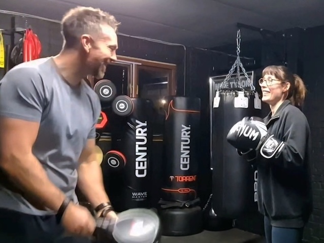 Female boxer training with coach using focus mitts at Boxing Fitness MK gym in Milton Keynes